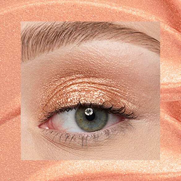 Close-up of an eye area with NYX Professional Makeup Lid Lingerie Cream Eye Pigment in Gold String, shown on a gold shimmer textured background.