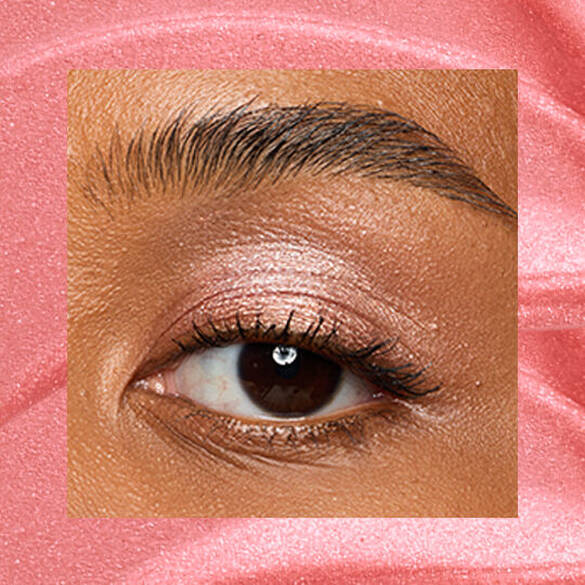 Close-up of an eye area with NYX Professional Makeup Lid Lingerie Cream Eye Pigment in Risky Rose, shown on a rose gold shimmer textured background.